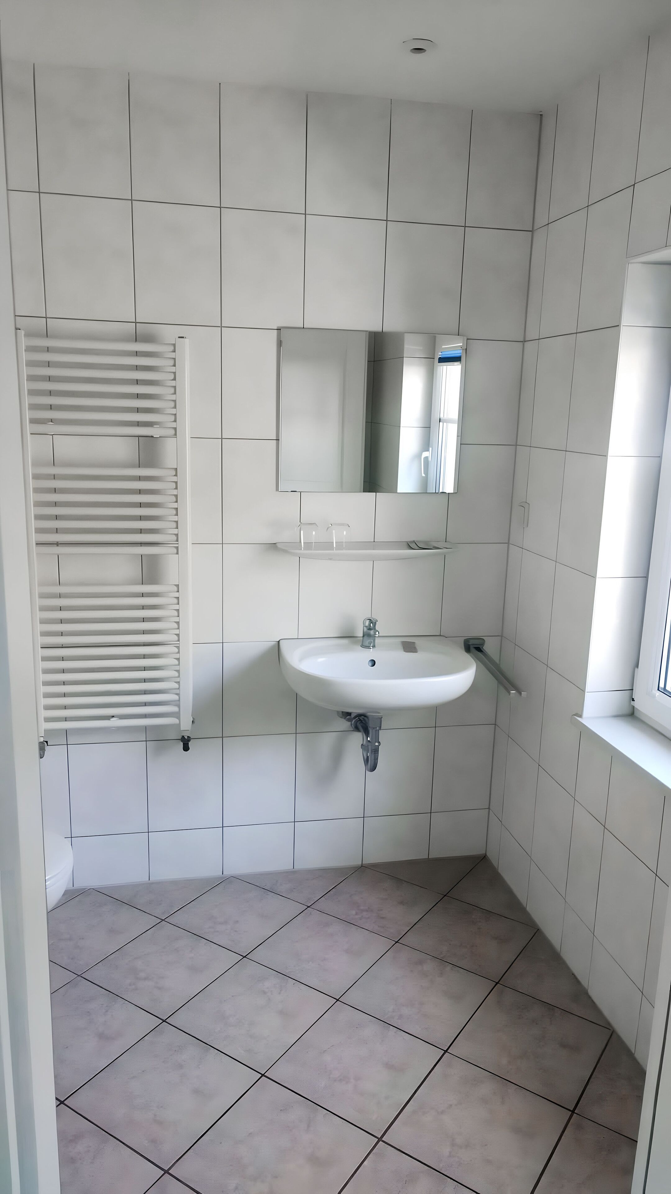 Ein Badezimmer mit einem weißen Waschbecken, einem Spiegel und einem Handtuchhalter.