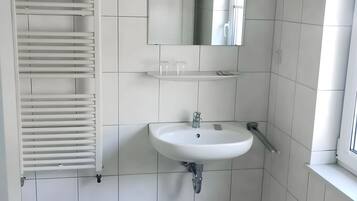A bathroom with a white sink, a mirror, and a towel rack.