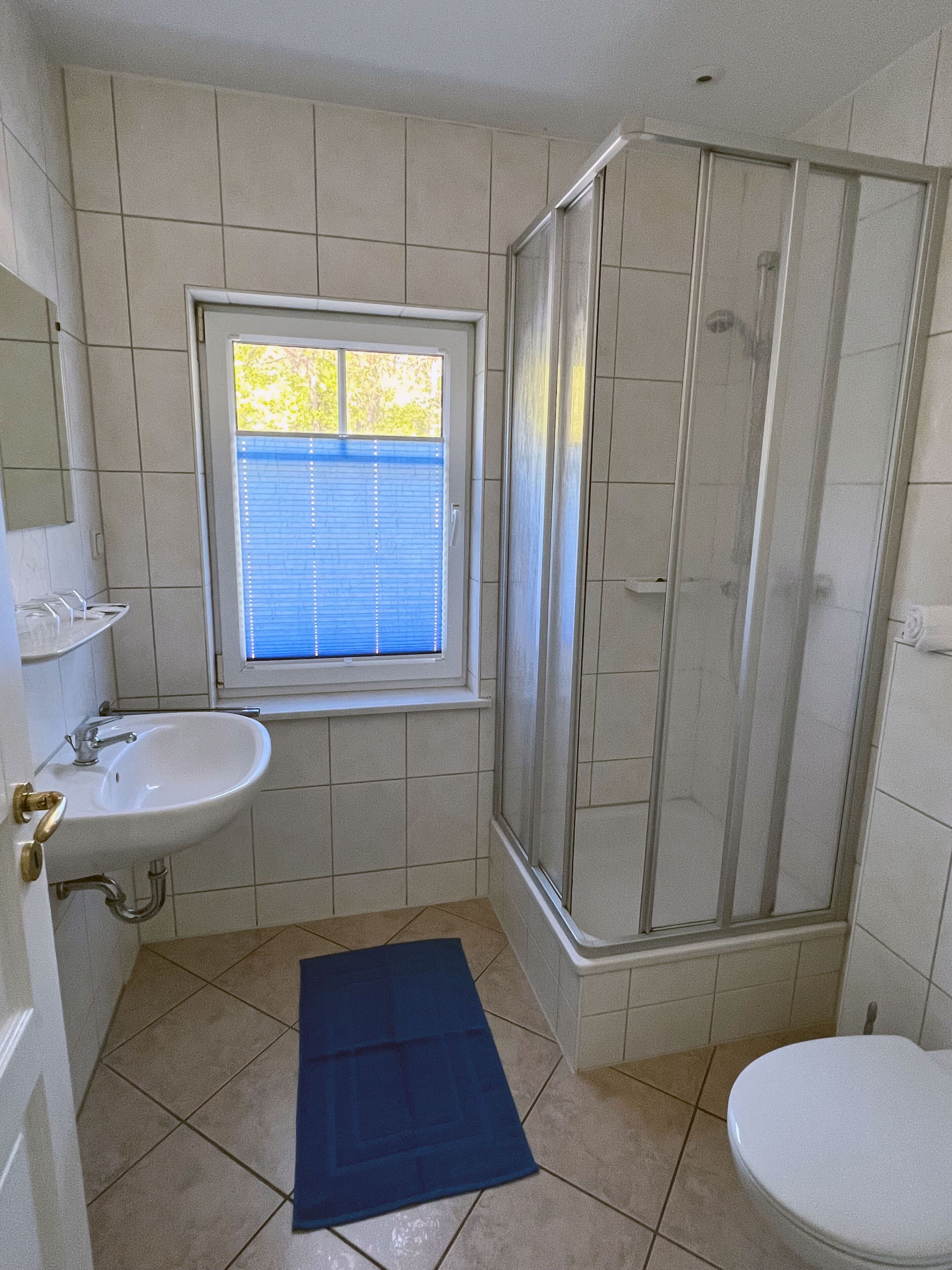 Une salle de bain équipée d’un lavabo, d’une fenêtre, d’une douche et de toilettes.