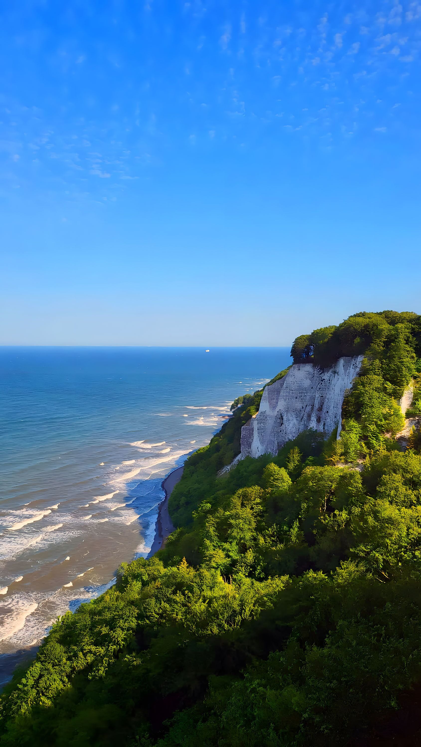 A coastal landscape with cliffs, greenery, and the ocean.