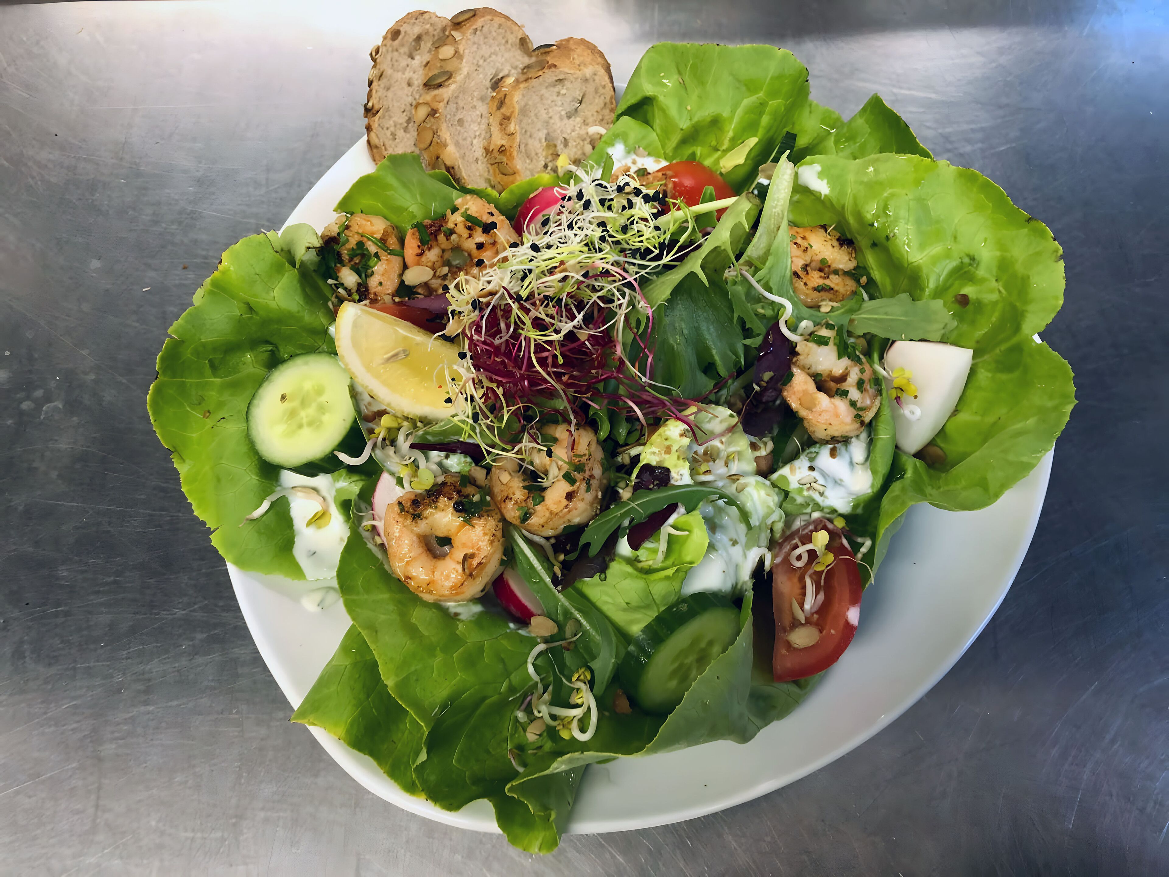 A salad with various vegetables and shrimp, served on a white plate.