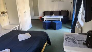 A hotel room with a bed, a desk, a chair, a sofa, and a window with curtains.