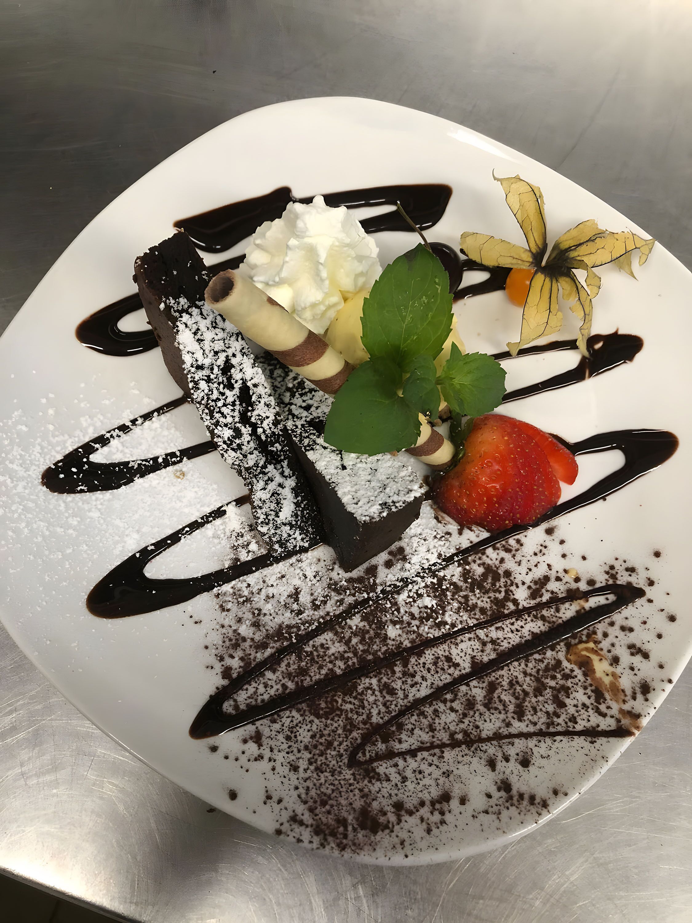 Une assiette de dessert avec du chocolat, de la crème fouettée et une fraise.
