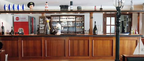 Eine Bar mit Holzwandverkleidung, einem Coca-Cola-Kühlschrank und einer Auswahl an Flaschen und Gläsern.