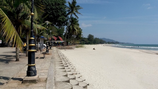 A beach with a paved walkway lined with palm trees and street lamps. - OYO 90818 Cemara Puri Resort & Spa  (Kuantan)