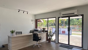 A modern reception area with a wooden desk, black office chair, and potted plants. - OYO 90818 Cemara Puri Resort & Spa  (Kuantan)