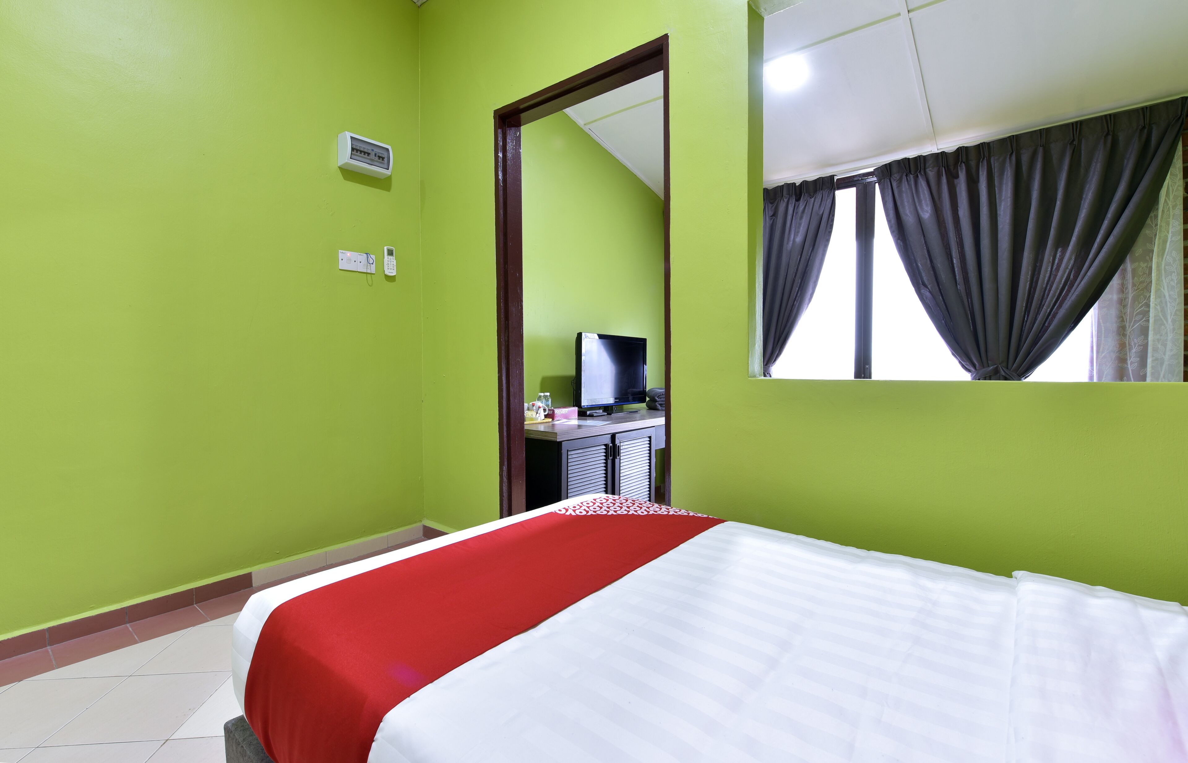 A room with a bed, a desk, a chair, a mirror, and a window with curtains.