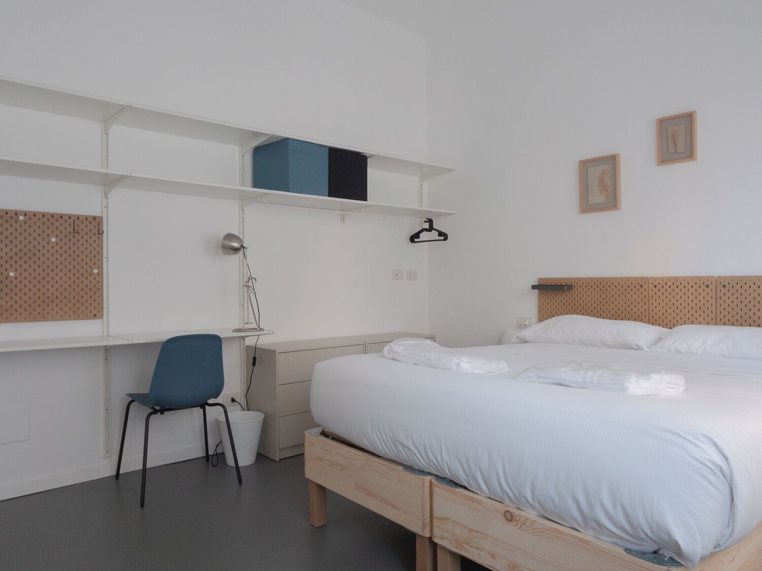 Un dormitorio minimalista con una cama individual, un escritorio y una silla.