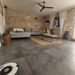 A modern living room with a stone wall, a grey sectional sofa, a wooden coffee table, and a black floor lamp.