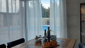A dining area with a table set for two, featuring a bottle of olive oil, a glass carafe, bread, and a small bowl.