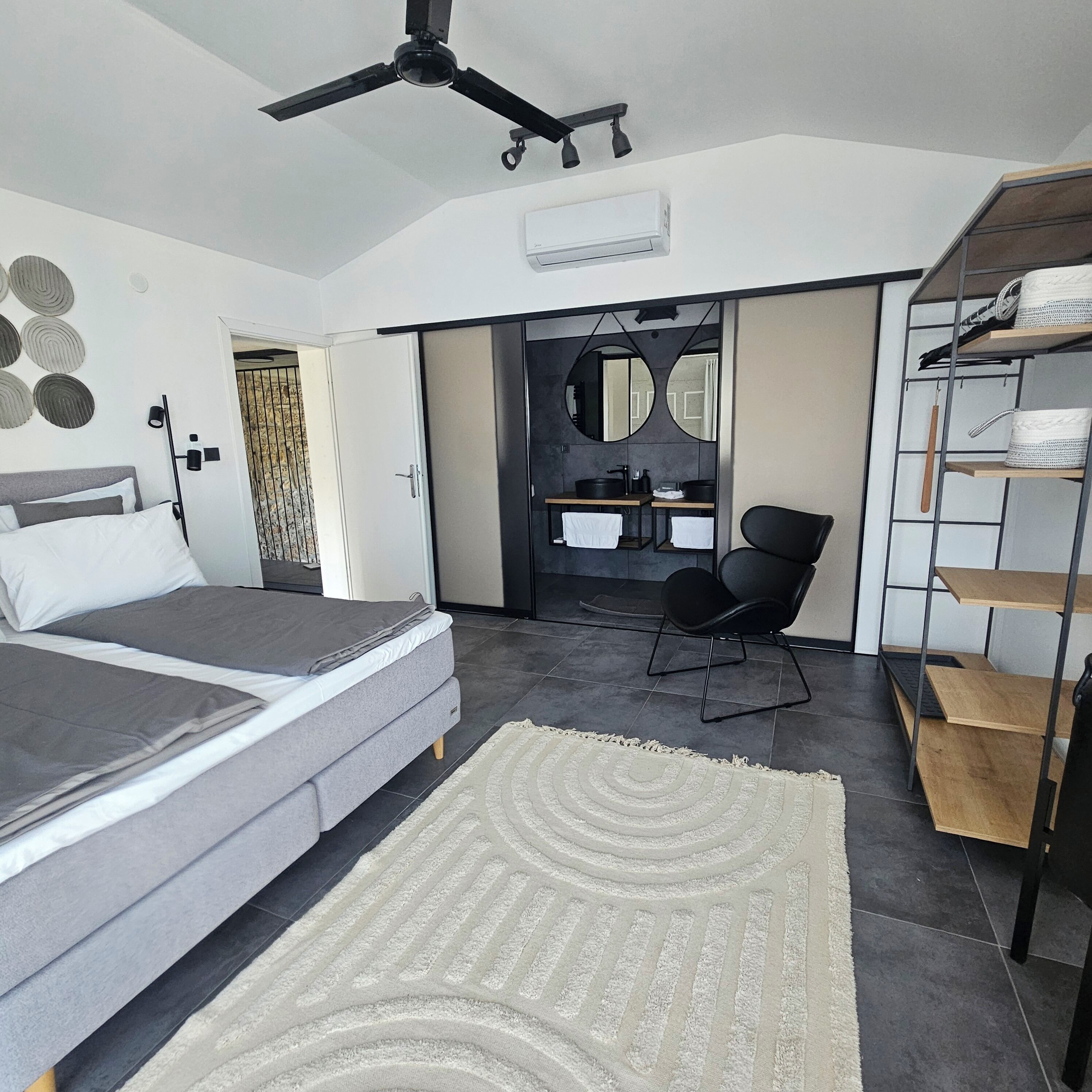 A modern bedroom with a bed, a desk, a chair, and a wardrobe.