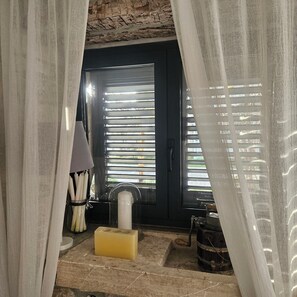 A bathroom with a bathtub, a toilet, and a sink. There is a curtain partially drawn, revealing a window with blinds.
