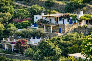 Una proprietà collinare con edifici in pietra, una pergola e vegetazione rigogliosa.