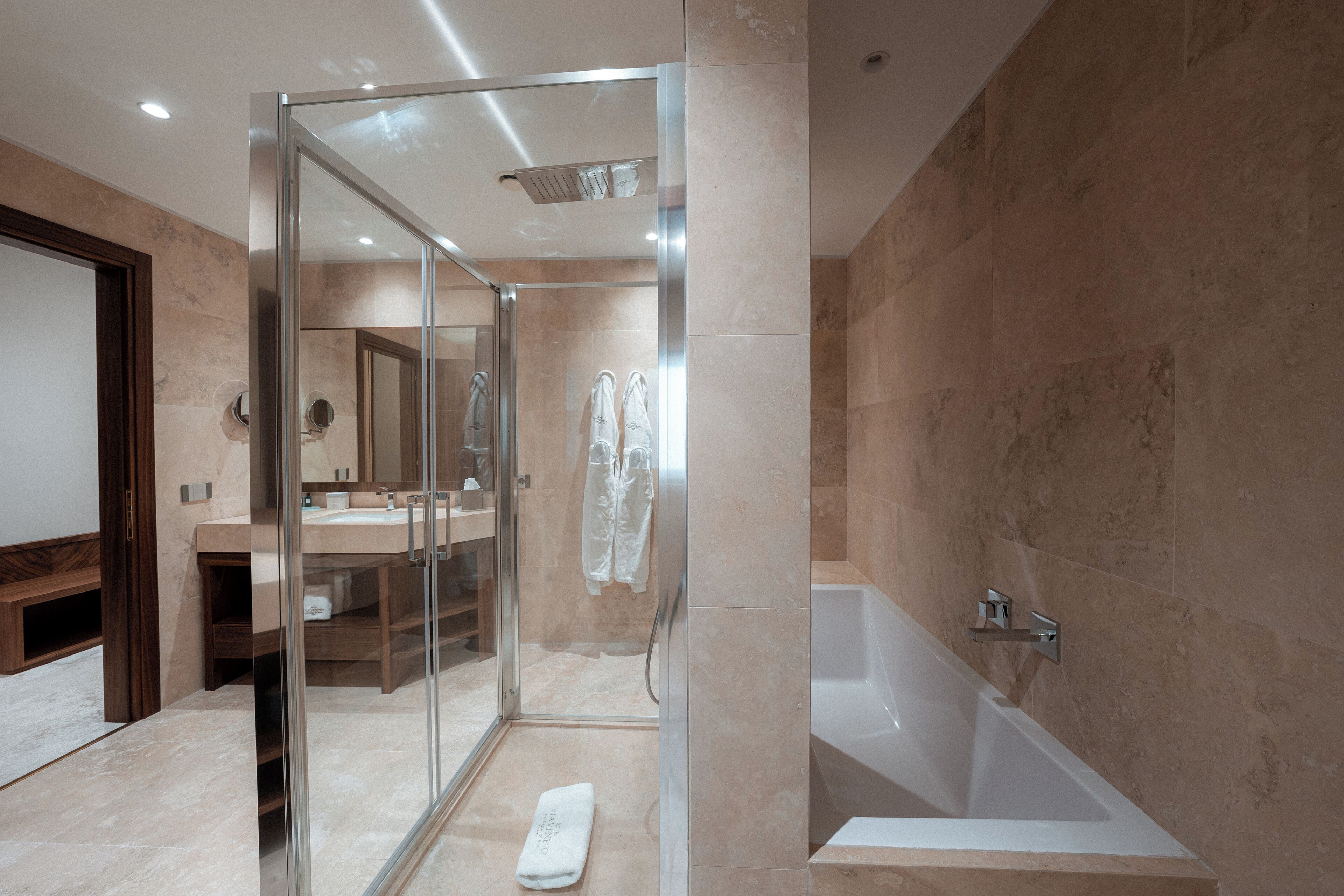 Un baño moderno con ducha acristalada, bañera y tocador con espejo.