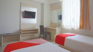 A hotel room with two beds, a desk, a chair, a TV, and a window with curtains. - OYO 3269 Hotel Grand Sayang Park Makassar (Makassar)
