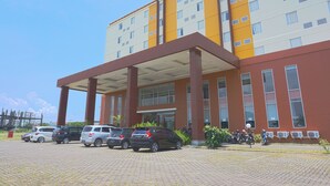 A multi-story hotel with a covered entrance, several parked cars, and motorcycles in front. - OYO 3269 Hotel Grand Sayang Park Makassar (Makassar)