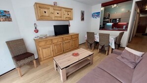 Un salon comprenant un meuble en bois, un téléviseur, des fauteuils en osier, une table basse en bois et un canapé.