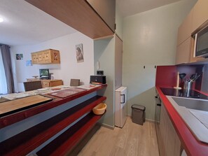 A compact kitchen with a microwave, a small refrigerator, and a sink. There is a dining table with chairs and a small rug. - Renovated studio, 4 pers, near slopes (Les Deux Alpes)