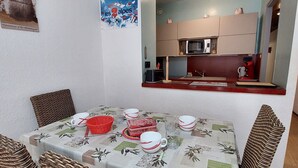 Un coin repas avec une table dressée pour quatre personnes, une cuisine équipée d’appareils modernes et un tableau encadré au mur.