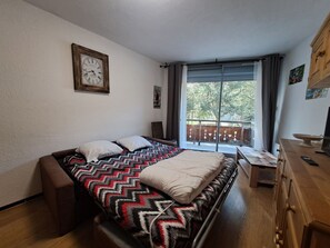 Un dormitorio con cama, ventana con cortinas, cómoda de madera y un reloj de pared.