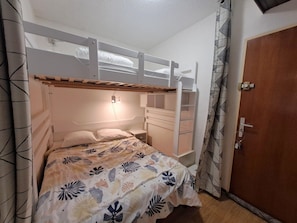 Habitación con literas, una mesita de noche y una puerta.