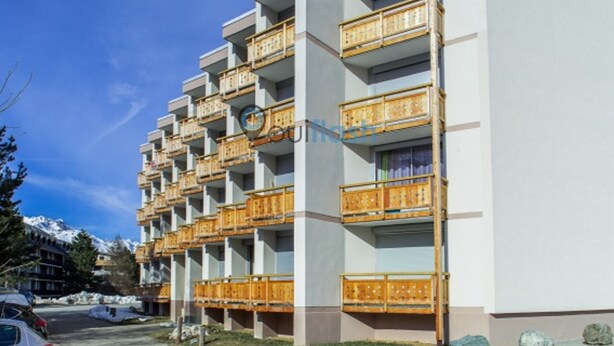 Un hôtel à plusieurs étages doté de balcons, d’un parking et situé dans un cadre montagneux.