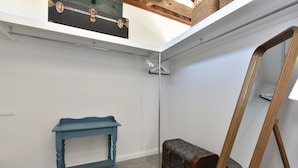 Um quarto com uma mesa azul, um baú e uma escada de madeira.