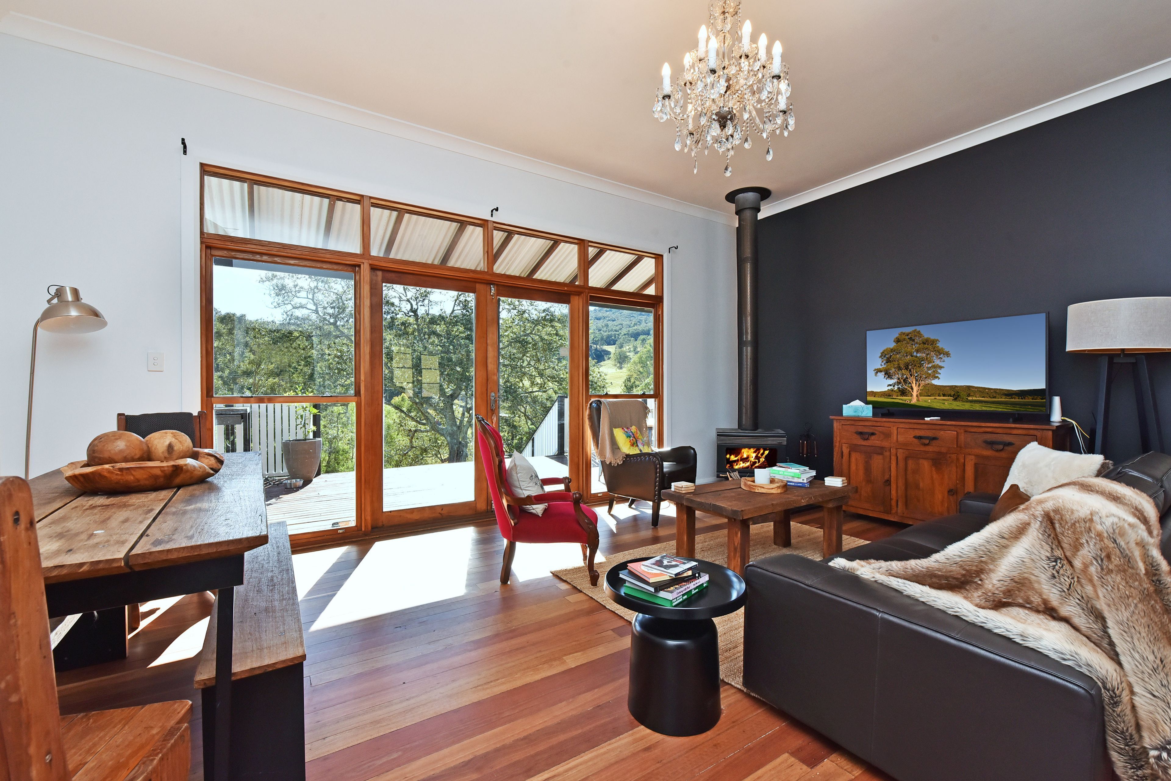 A spacious living room with a large sliding glass door leading to an outdoor deck, a fireplace, and a television mounted on the wall.
