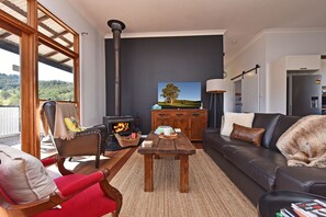 Uma sala de estar moderna com lareira, um sofá, uma poltrona vermelha e vista para o exterior.