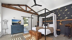 Quarto com cama de dossel, ventoinha no teto, televisão e guarda-roupa.
