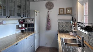 Een keuken met een houten aanrecht, een roestvrijstalen spoelbak en een klok aan de muur.