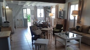 Een ruime woonkamer met een eettafel, stoelen, een bank en een salontafel.