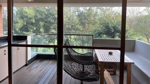 Un balcón con ventilador de techo, una mesa y una silla.