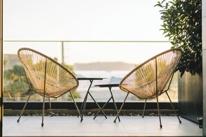 A balcony with two wicker chairs and a small table, overlooking a scenic view. - Akana Loft (Bodrum)
