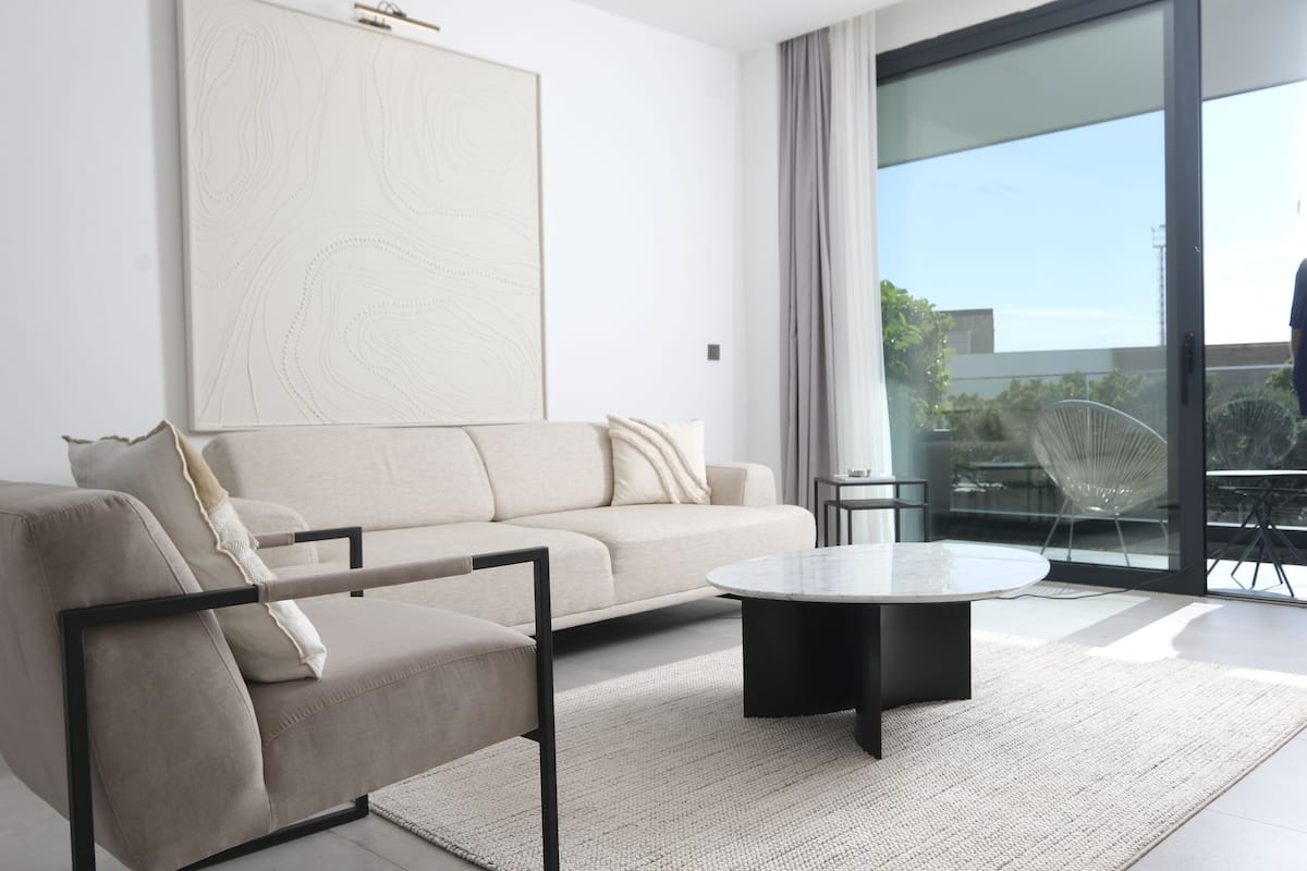 A modern living room with a sofa, a coffee table, and a large abstract painting on the wall.