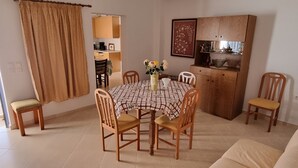 Ett mysigt vardagsrum med ett matbord, stolar, en soffa och ett kök i bakgrunden.