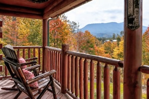 A wooden deck with a wooden railing, a rocking chair, and a signpost with text.