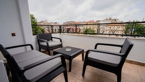 Ein Balkon mit zwei schwarzen Korbsesseln, einem kleinen Tisch und einem dekorativen Metallgeländer.