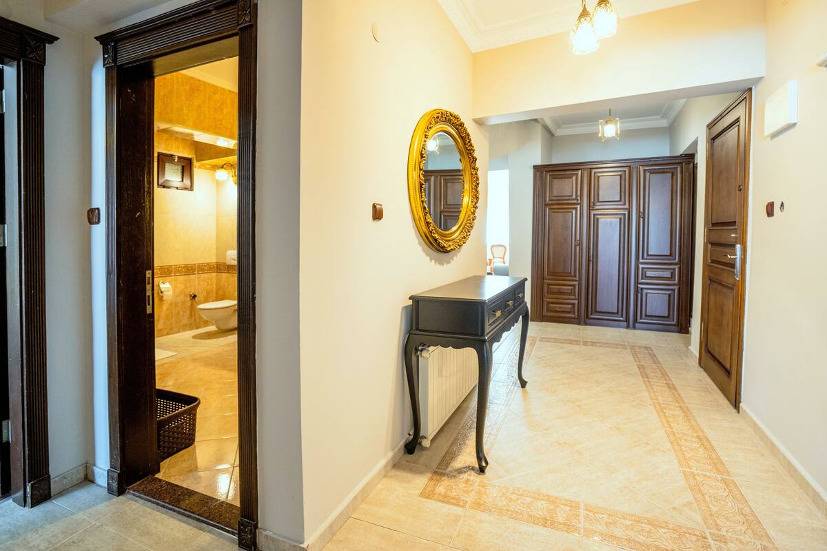 A hallway with a wooden door, a mirror, a radiator, and a radiator cover.