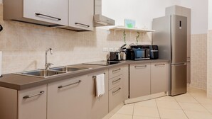 A modern kitchen with stainless steel appliances, a sink, and a countertop. - BnButler - Pellegrino Rossi 42 (Milan)