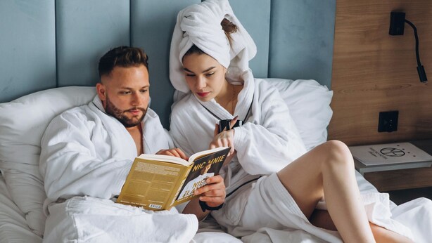 A couple in a hotel room, reading a book together. - Mielno Hotel Boutique (Mielno)