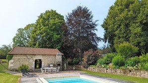 A swimming pool with a stone building and outdoor seating area. - Charming Gîte with Heated Pool, Garden, BBQ, and Baby Equipment Near Aubeterre-sur-Dronne (Bellon)