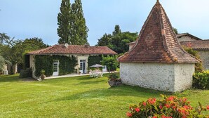 A traditional stone house with a red-tiled roof, a small garden with a lawn, and a white gazebo. - Charming Gîte with Heated Pool, Garden, BBQ, and Baby Equipment Near Aubeterre-sur-Dronne (Bellon)