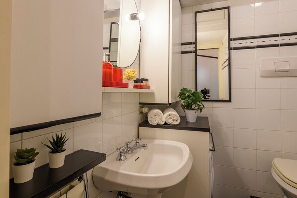 Un baño con lavamanos, espejo, toallero y plantas en macetas.
