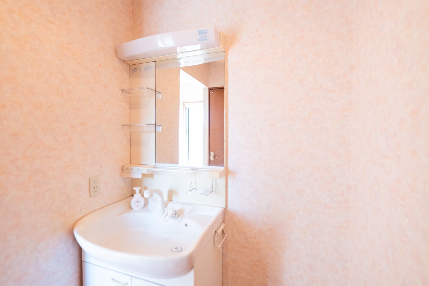 A bathroom with a white sink, a mirror, and a towel rack.