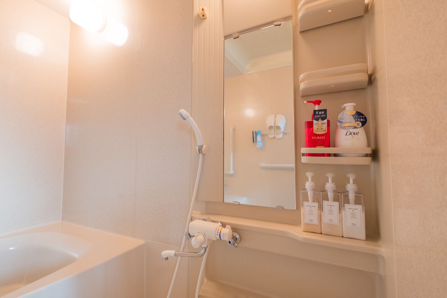 A bathroom with a bathtub, a shower, and a shelf with toiletries.
