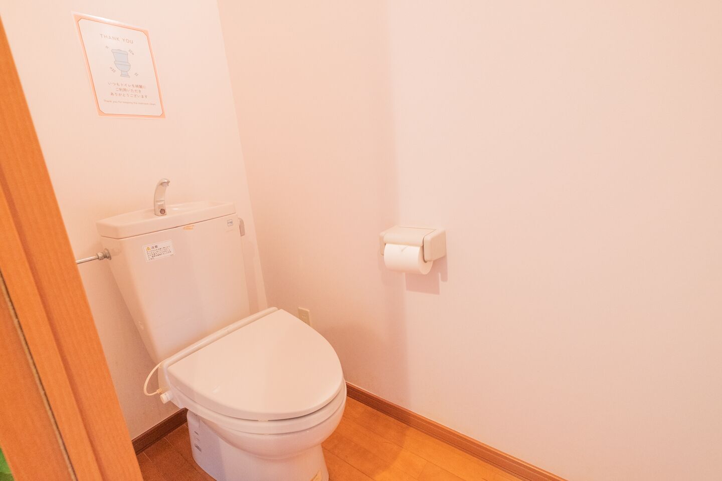 Ein kleines, sauberes Badezimmer mit Toilette, Toilettenpapierhalter und einem Schild an der Wand.