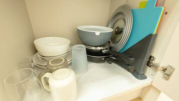 A kitchen counter with various dishes, a kettle, and a blue storage rack.
