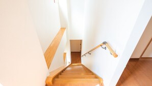 Un escalier en bois avec une rampe et une main courante en bois fixée au mur.