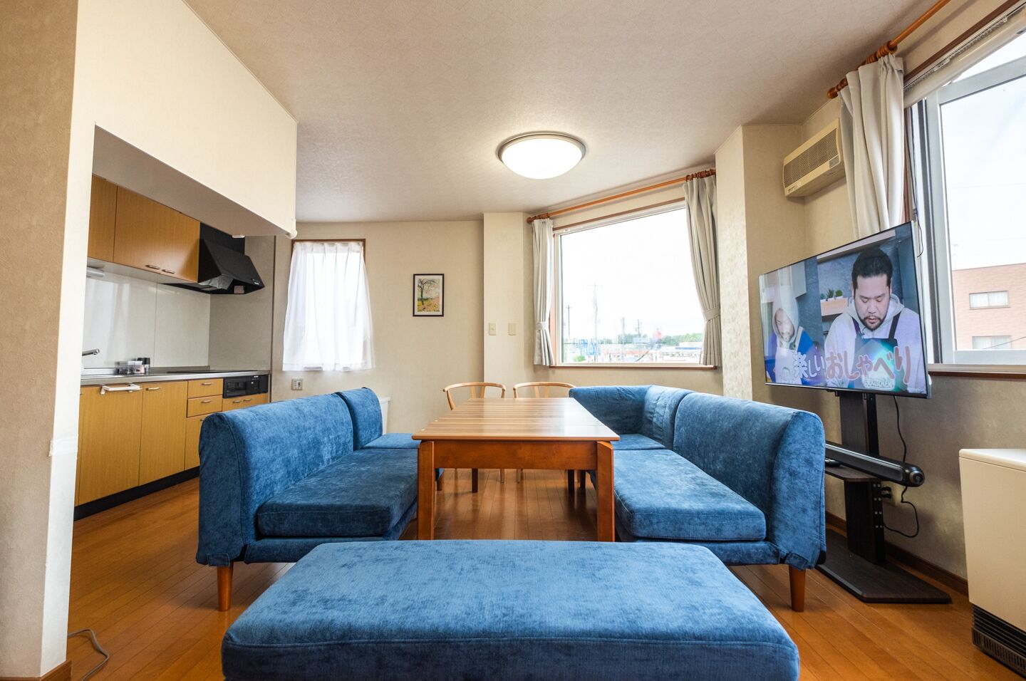 A compact living space with a kitchenette, a dining table, a sofa, and a television.